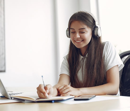 a girl listening in headphones and writting notes